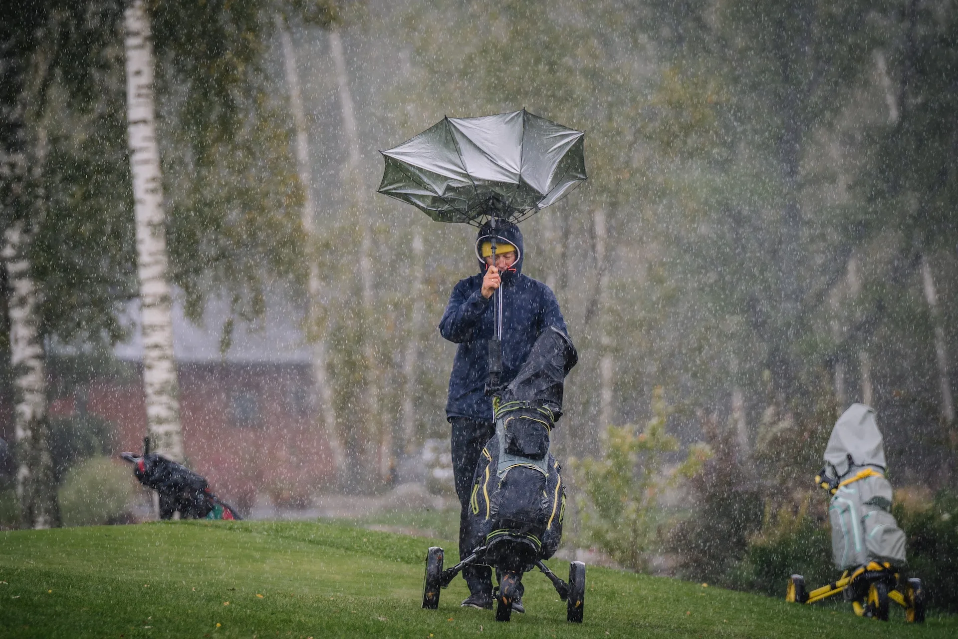 Golfer on a Rainy Day Leaving the Golf Course. The man is leaving the umbrella